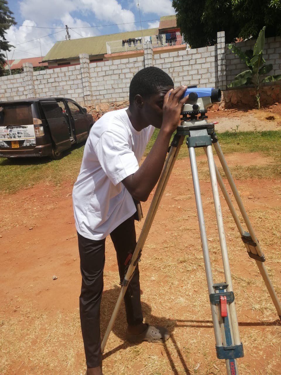 Alia sighting through a surveying level mounted on a tripod